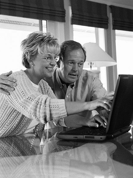 Happy couple searching for home inspector on their computer