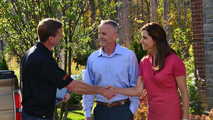 Contractor shaking hands with smiling homeowners